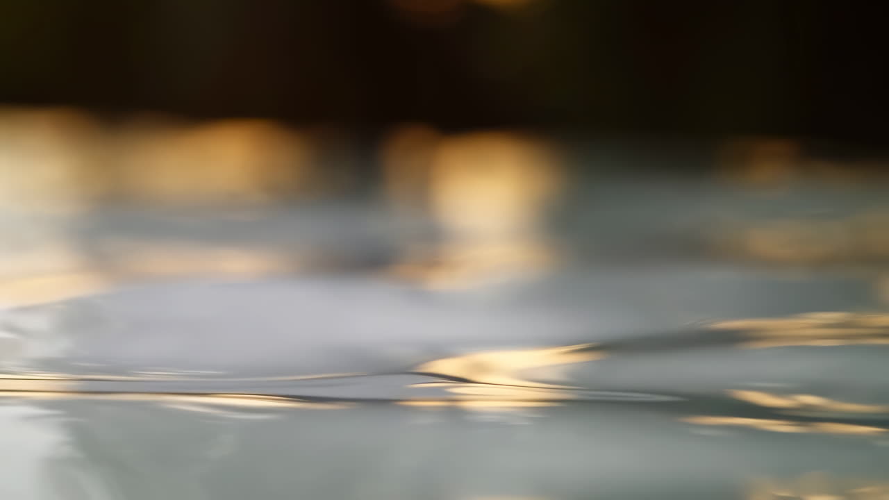 Calm Water Surface with Ripples and Golden Light Reflections