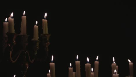 a group of white candles some on a candelabra lit up and running for a while