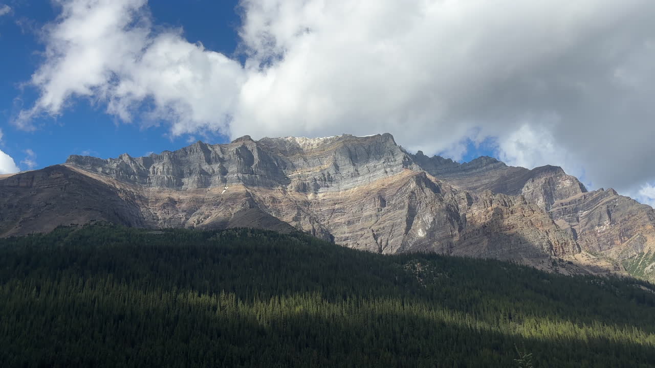 Majestic mountain illuminated by sunlight, clouds passing by, Banff, Canada. Handheld