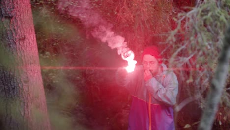 man with a red flare in the woods at night