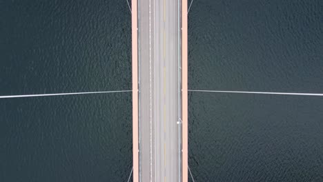 cables poderosos que sostienen el puente colgante hardangerbrua - antena birseye que se mueve hacia adelante sobre el puente con cables que pasan cerca - mar hardangerfjorden debajo - noruega