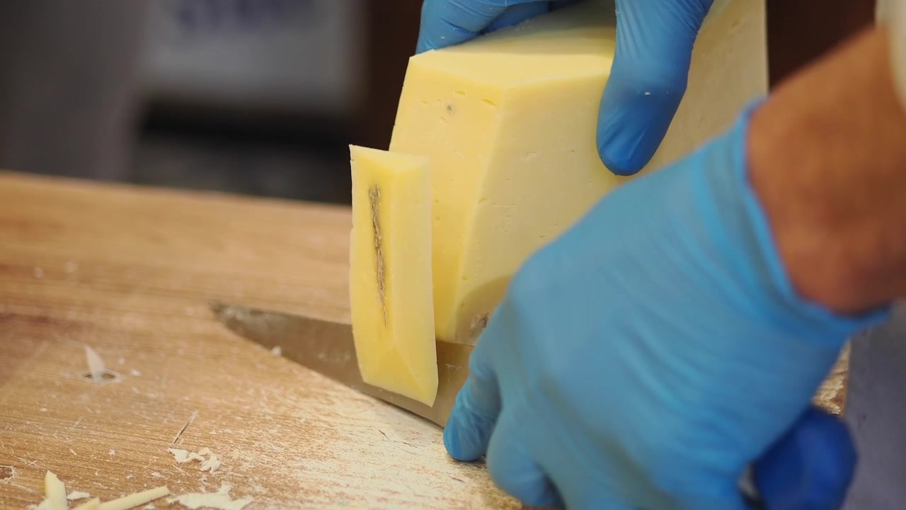 Chef cortando un bloque de queso fresco en una cocina profesional