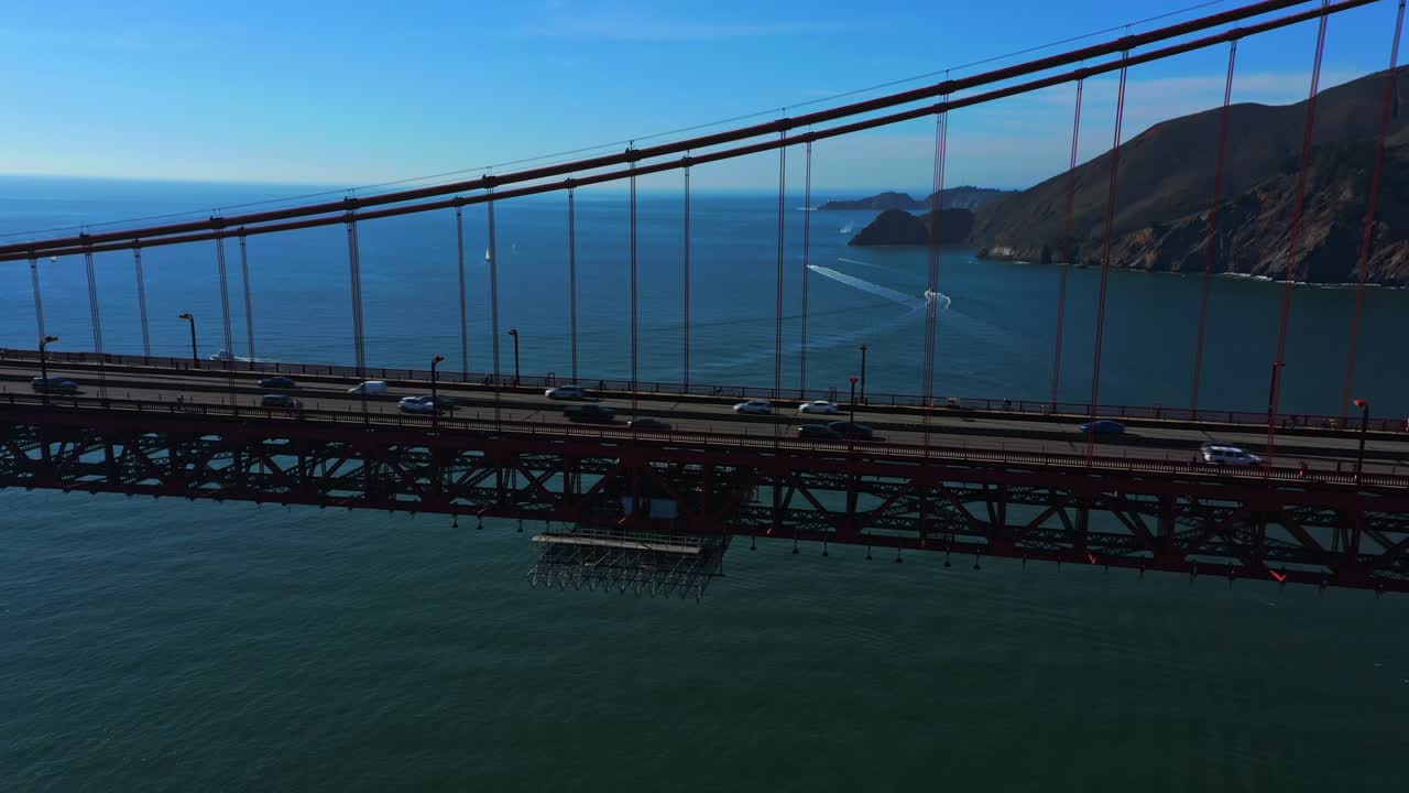 Aerial reveal of cars and trucks traveling on the San Francisco Golden Gate Bridge.