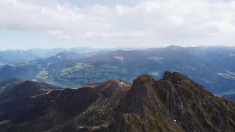 Filmische-Luftaufnahme-Des-Alpengipfels-Mit-Alter-Holzkapelle-Auf-Steilem-Gipfel