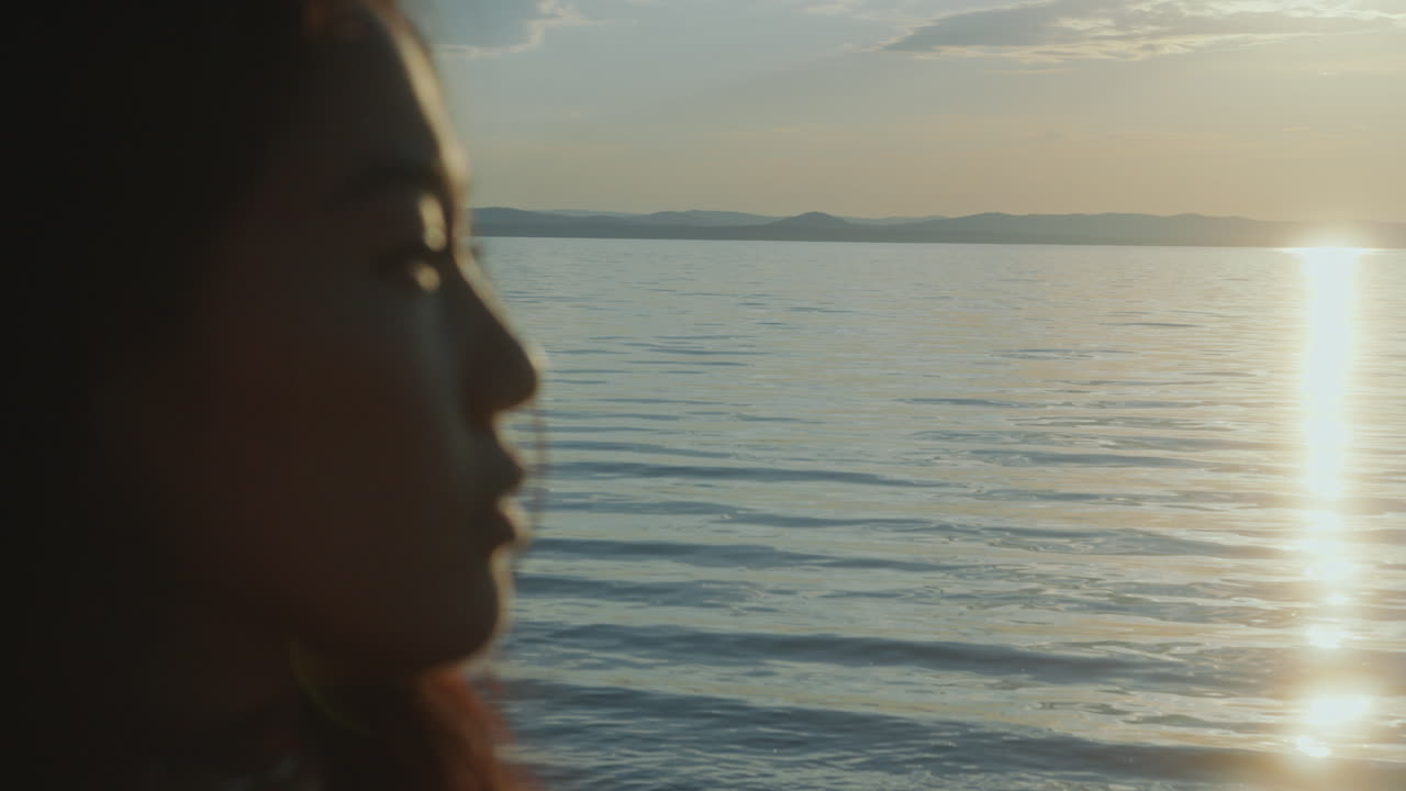 joven contemplativa mirando la orilla del lago durante el atardecer