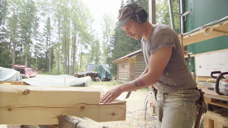 Profile shot of caucasian craftsman removing piece out of wood log with axe