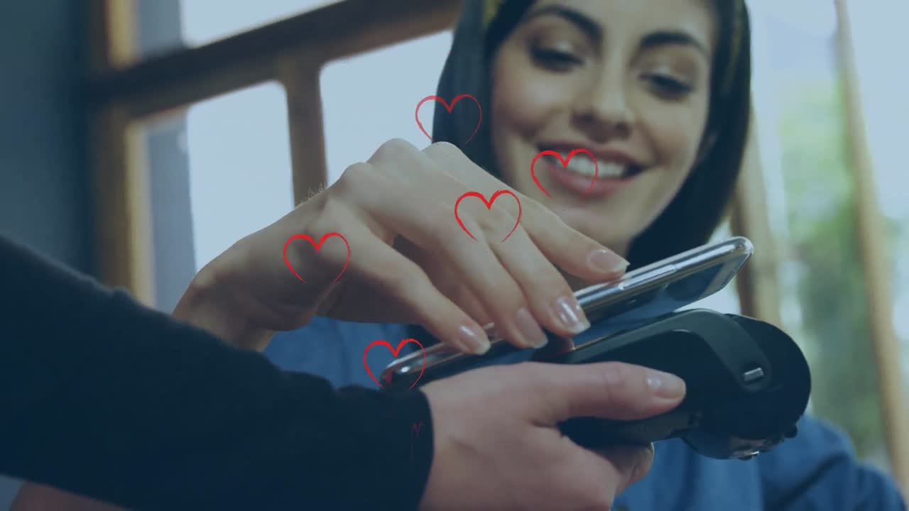 múltiples iconos de corazón rojo cayendo contra una mujer caucásica haciendo un pago desde su teléfono inteligente