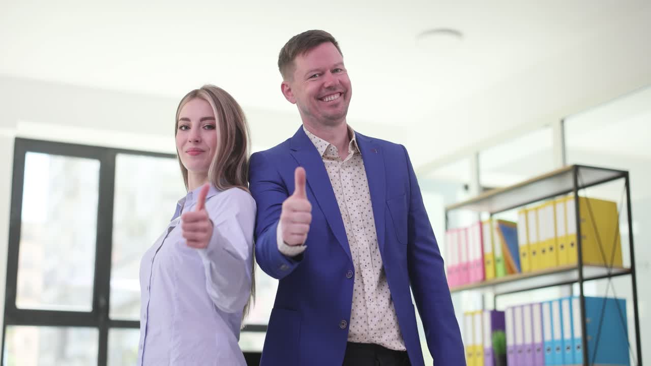 Man and Woman in Office Giving Thumbs Up