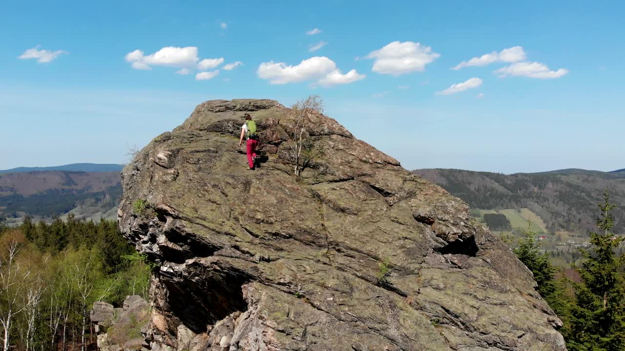 joven exitosa con los brazos levantados en la cima de la montaña.