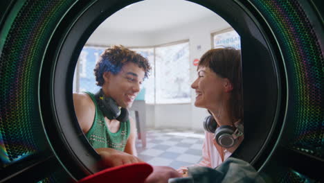couple talking public laundromat closeup. smiling friends wait in laundry room