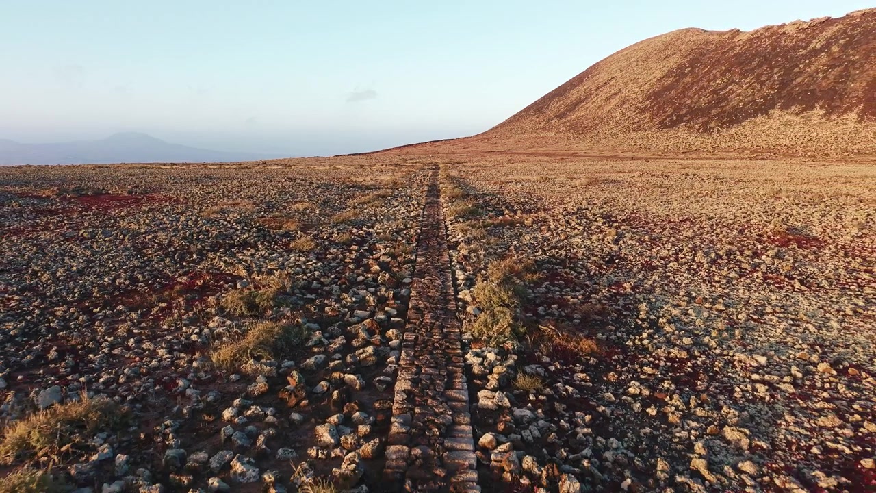 Sentiero di pietra che attraversa un paesaggio vulcanico al tramonto