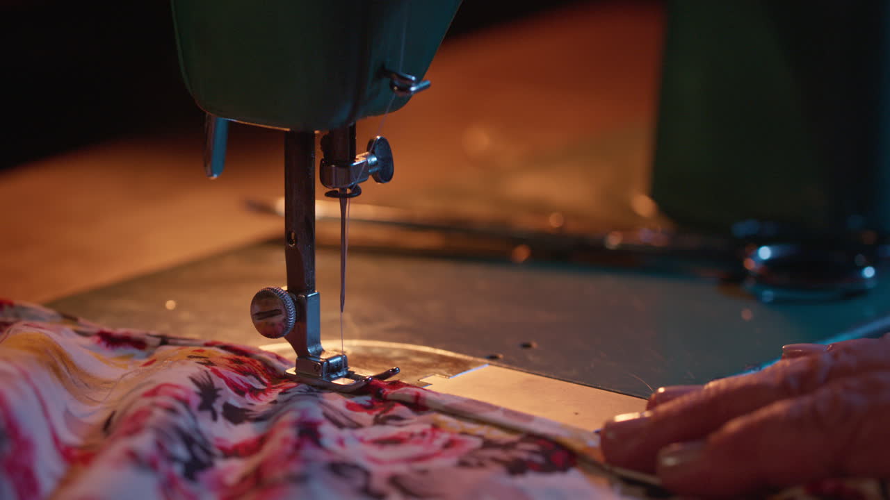 Close-up of Hands Guiding Floral Fabric on a Vintage Sewing Machine