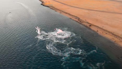 jet skis spin and do donuts in tropical ocean waters by a barren abu dhabi coastline