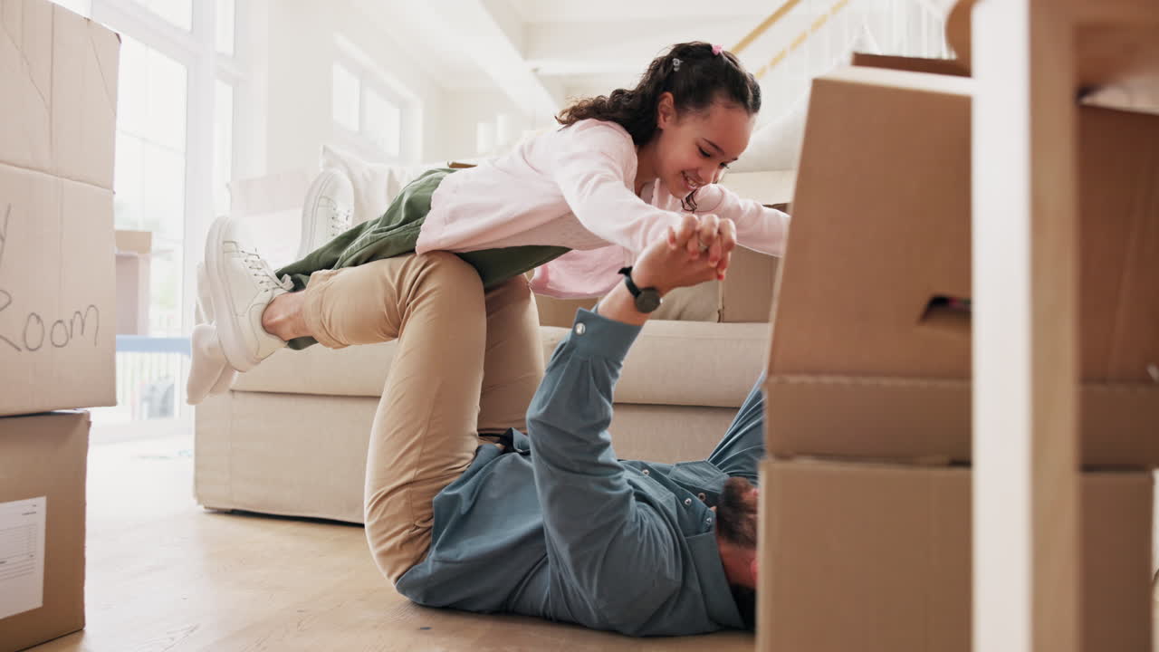 Father and daughter playing together in a new home surrounded by moving boxes