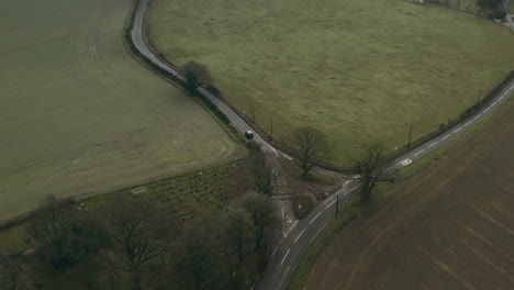 aerial drone shot following a car as it drives off in to the distance whilst revealing the surrounding landscape