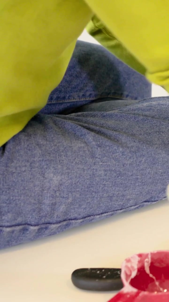 Vertical video: Spotting glass and remote, woman in lime sweater and jeans reaching on white table