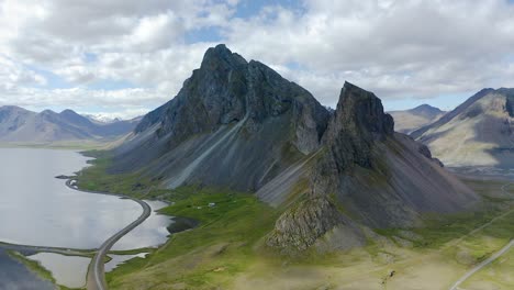 rugged, black steep mountain with green hillside, pan left to right, aerial