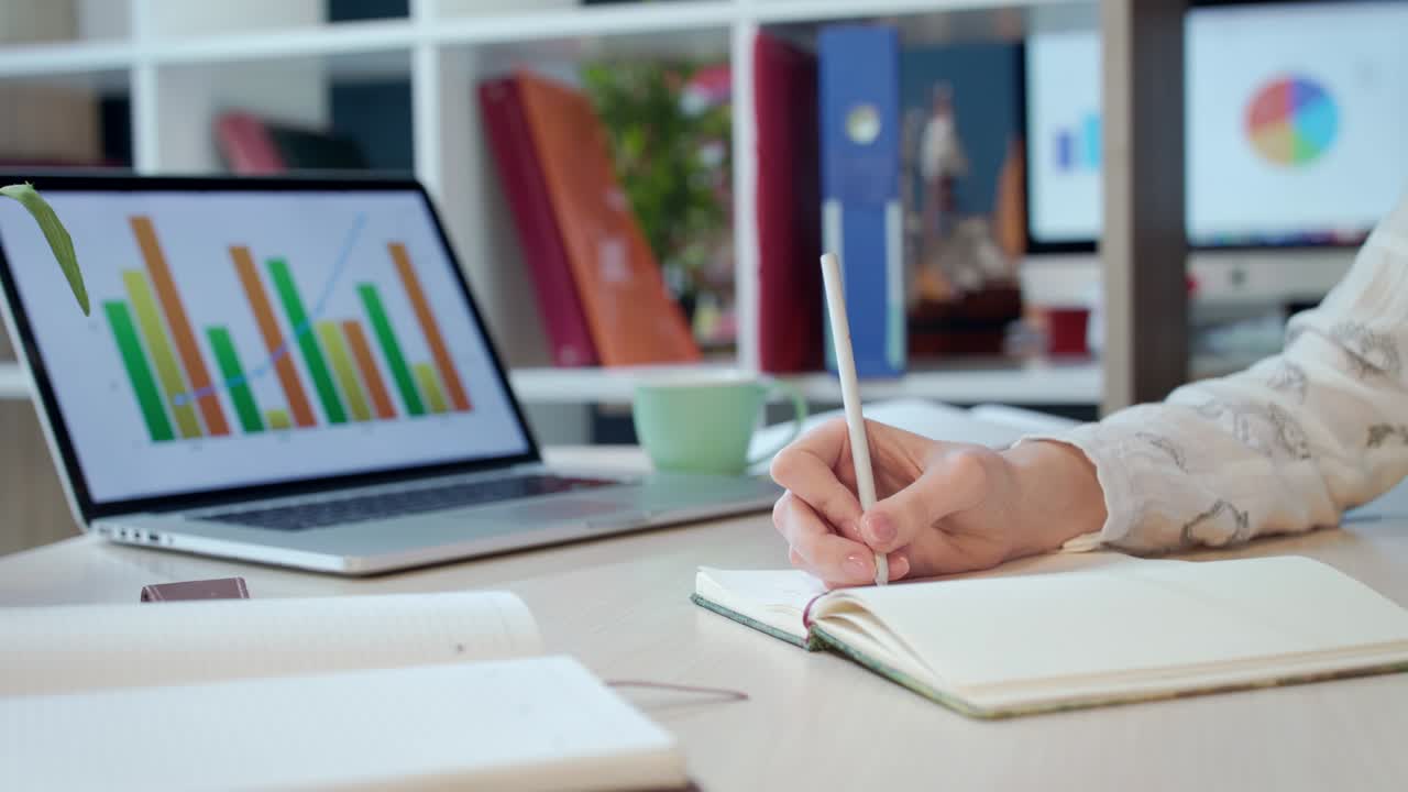 mujer escribiendo a mano en un cuaderno en el espacio de trabajo de una empresa moderna