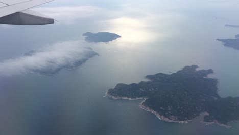 airplane in flight over picturesque island near hong kong at daytime