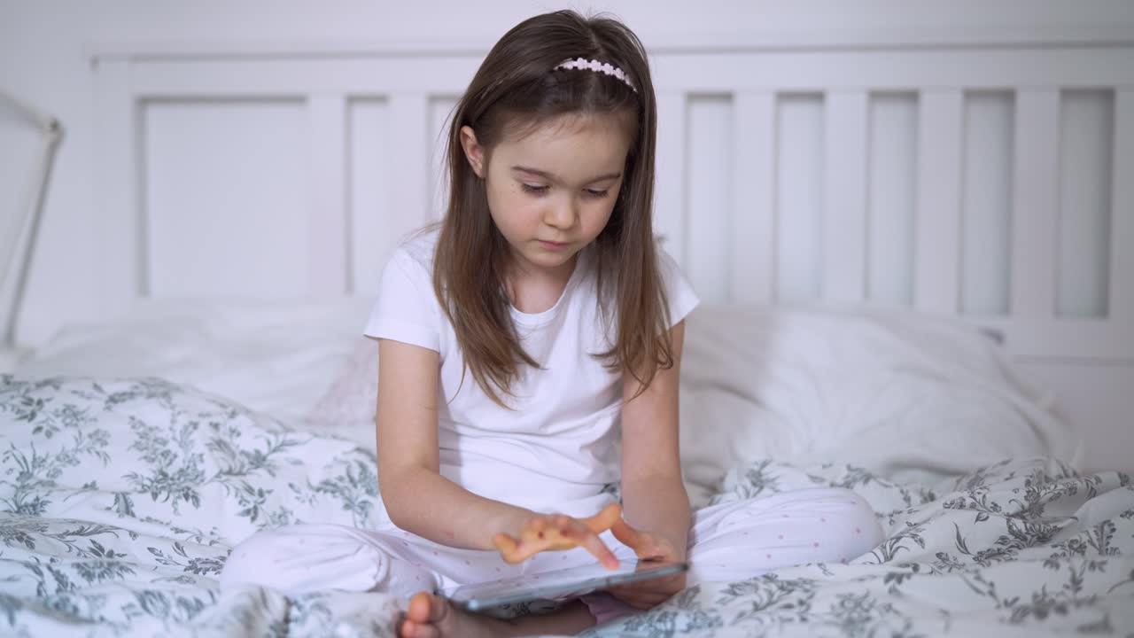 chica usando la tableta en la cama