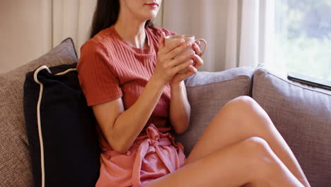 relaxing at home, woman holding coffee cup, enjoying peaceful moment on sofa