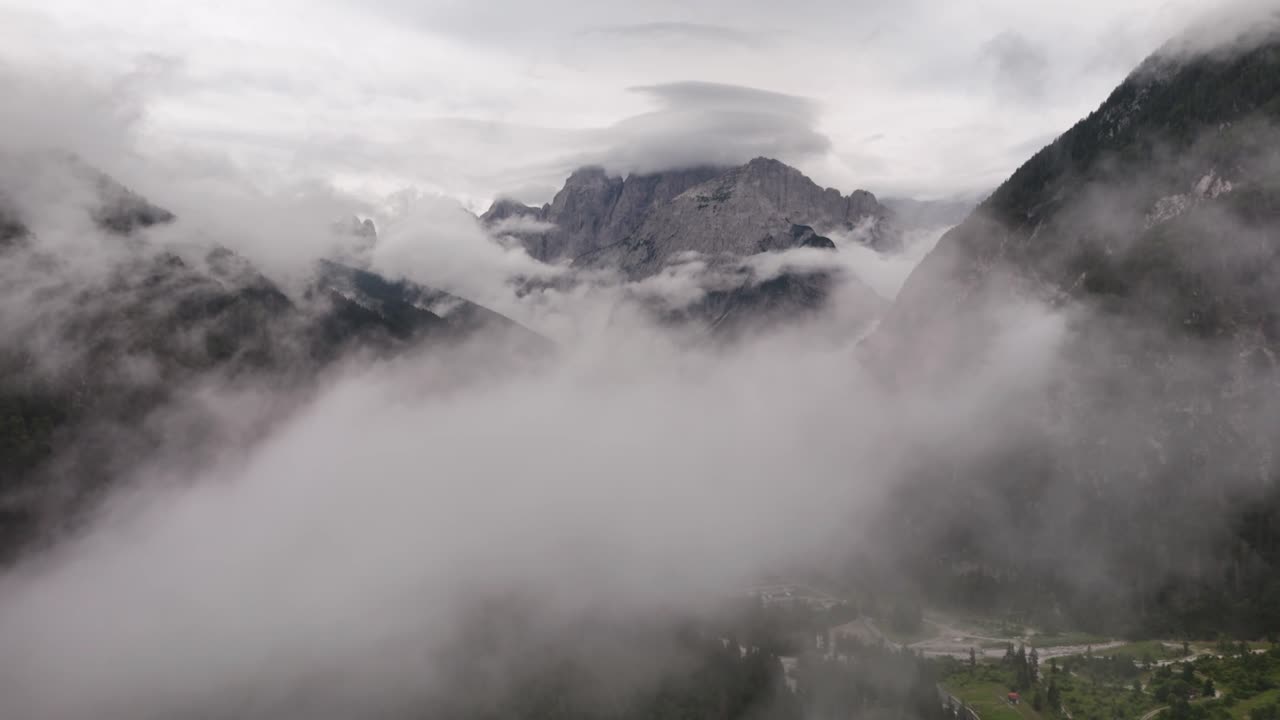 Drone aerial view of clouds drifting over the majestic peaks of the Alps mountains