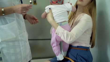 una madre joven sostiene a un bebé en sus brazos un médico examina