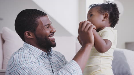 father sitting on floor and playing with baby daughter at home