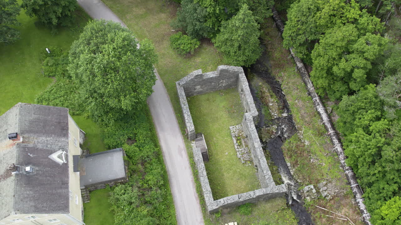 Parallax drone shot of ruins of Backefors Bruk ironwork with river in Bengtsfors Municipality, Sweden