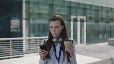 Retrato-De-Una-Hermosa-Joven-Sosteniendo-Un-Café-Y-Usando-Un-Teléfono-Inteligente-Durante-El-Descanso-Para-El-Almuerzo-En-El-Campus-De-La-Oficina-Corporativa-Al-Aire-Libre