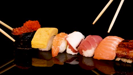 chopsticks select a piece of tuna nigiri from a neatly arranged sushi assortment on a glossy black surface under bright, even lighting