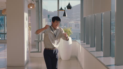 happy asian businessman dancing enjoying success with funny victory dance having fun feeling successful in office