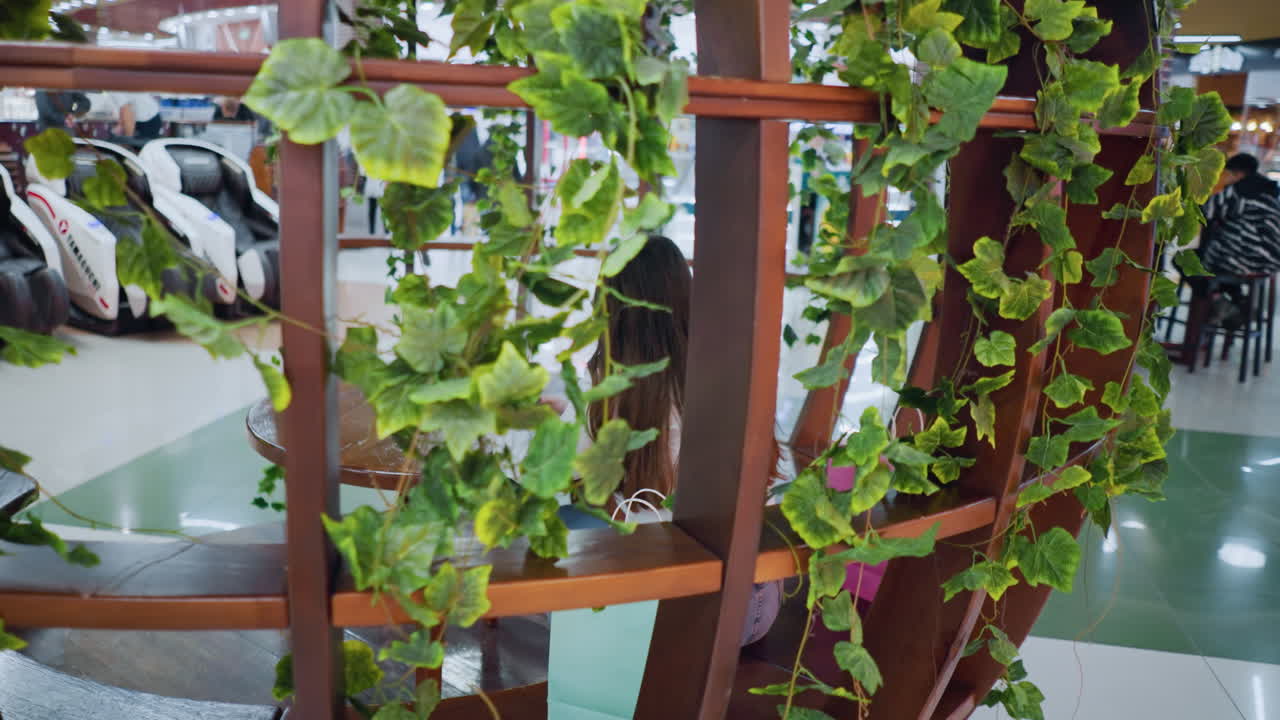 장식 된 나무 좌석에 앉아있는 멋진 젊은 여성, 에 쇼핑 가방을 들고, 쇼핑몰의 활기찬, 활기찬 분위기의 비는 배경에서 움직이는 사람들과 함께