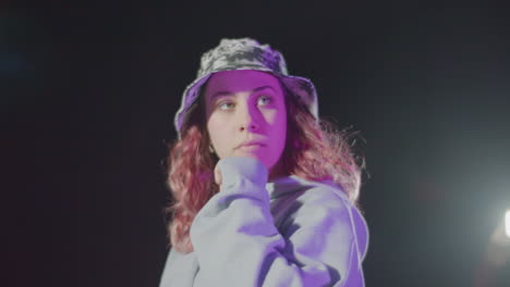 attractive young woman in hat posing in street at night