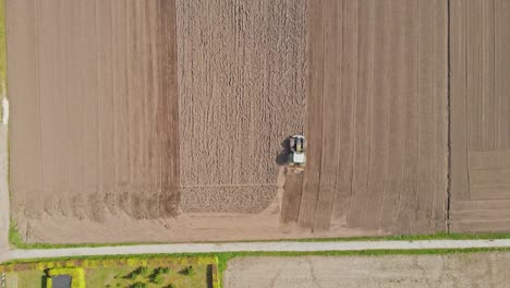 stunning top down aerial of tractor plowing a plot of empty land