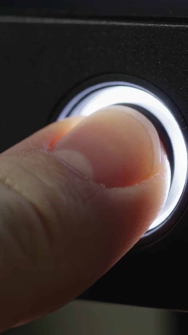 Vertical video: LED ring glowing, right thumb pressing and holding round power button to power unit