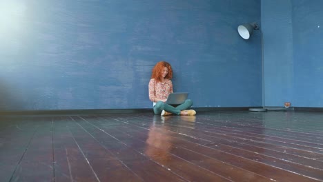 Woman working on laptop sitting on floor in home office