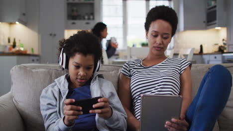 Madre-E-Hija-De-Raza-Mixta-Usando-Una-Tableta-Y-Un-Teléfono-Inteligente