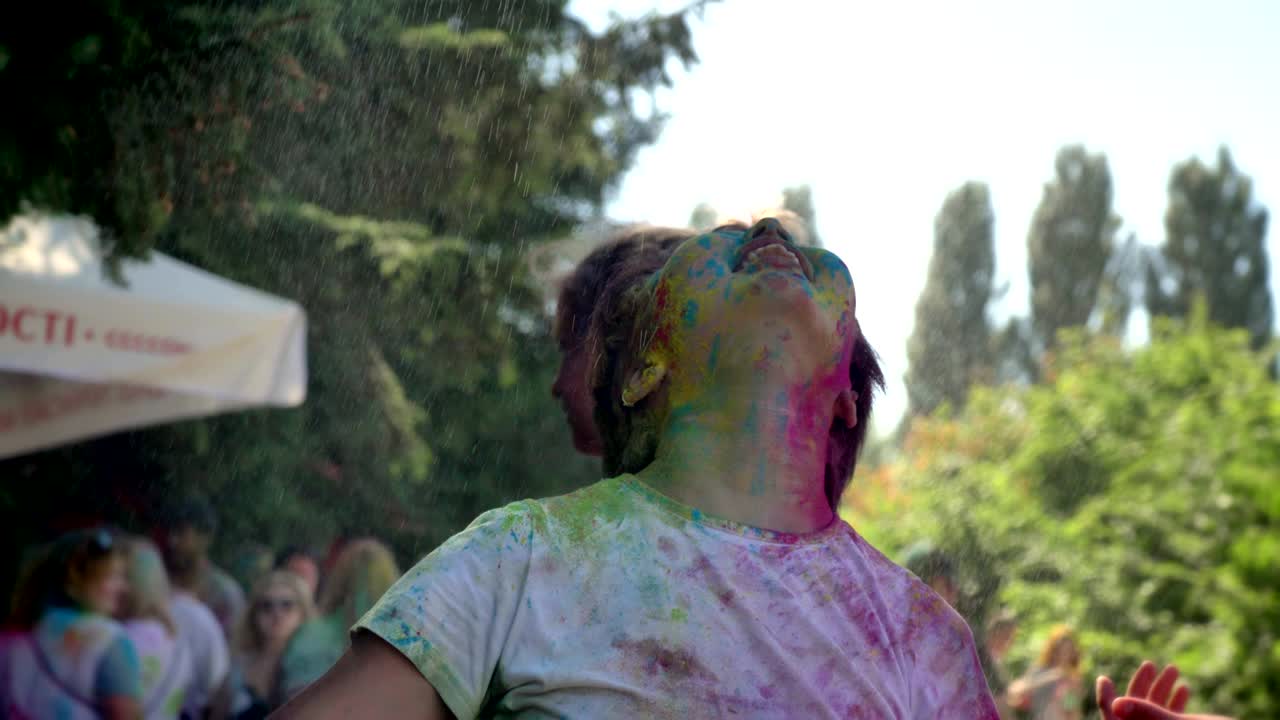 Young happy asian girl is raising hands under rain on holi festival in daytime in summer, color concept, emotional concept