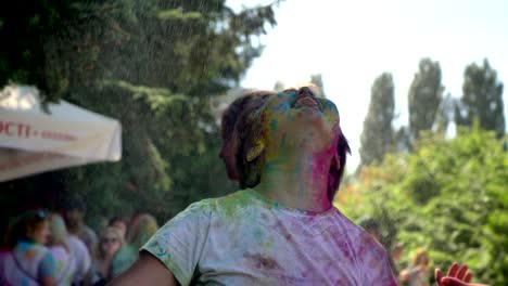 young happy asian girl is raising hands under rain on holi festival in daytime in summer, color concept, emotional concept