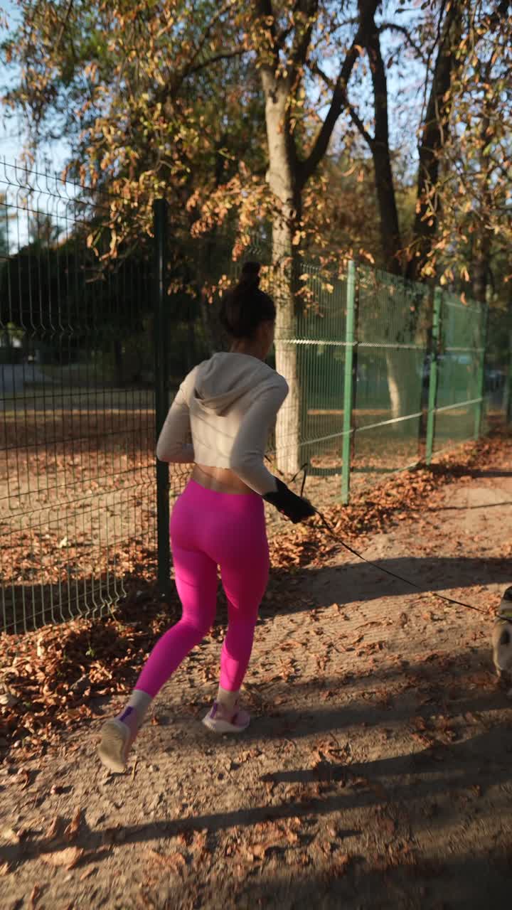 mujer corriendo con el perro en el parque de otoño