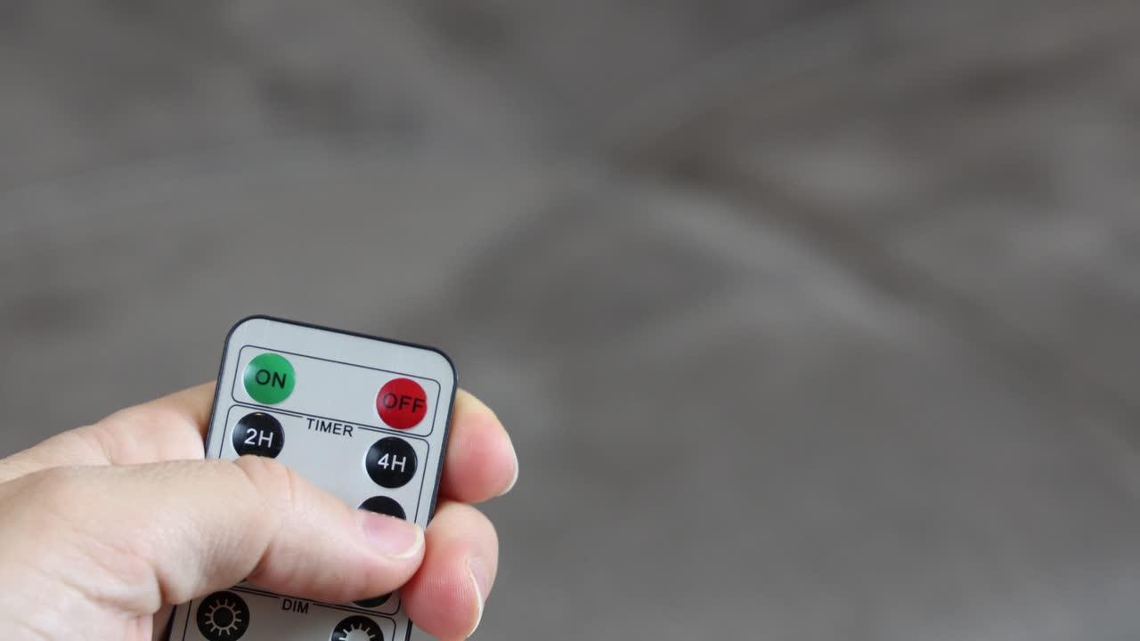 Pushing ON button on a remote control, close up