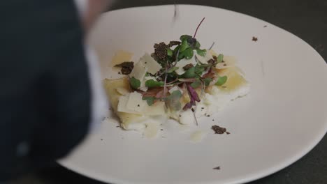 Tiny-truffle-shavings-flutter-onto-a-plate-of-pasta-adorned-with-microgreens-and-sauce