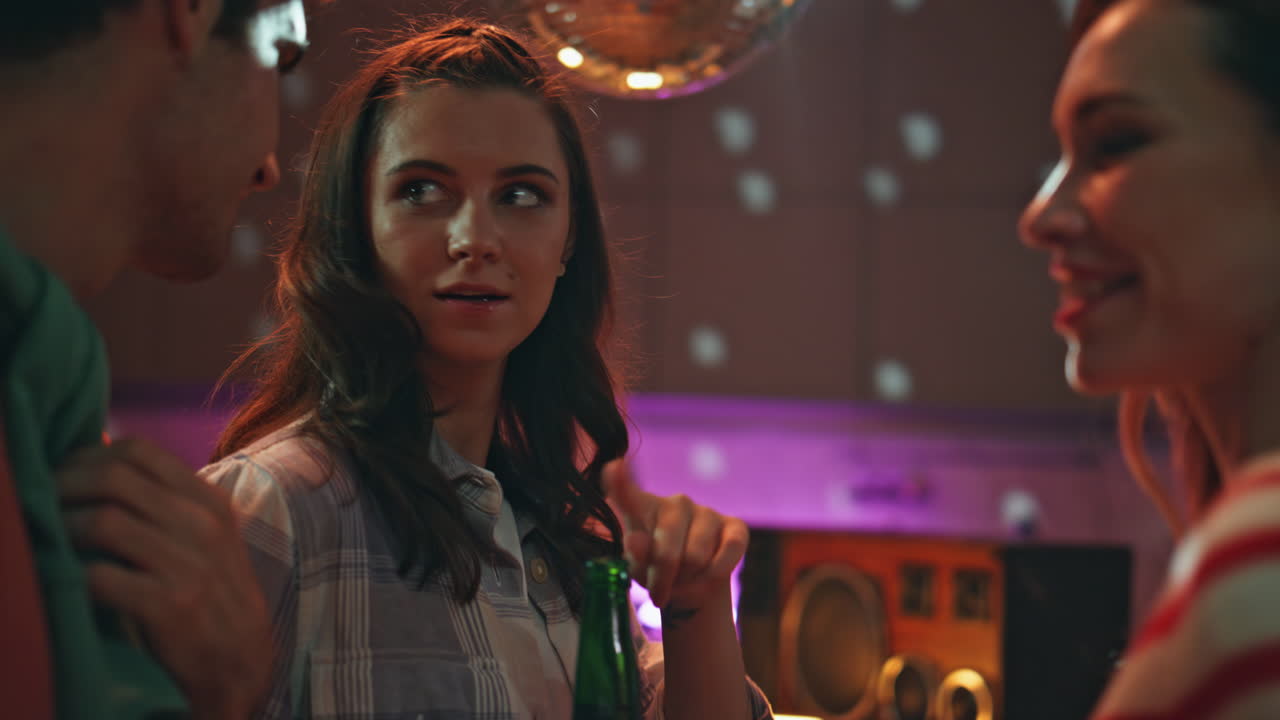 Nahaufnahme: Lächelnde Freunde genießen Disco-Treffen unter einer Lichtkugel zu Hause.
