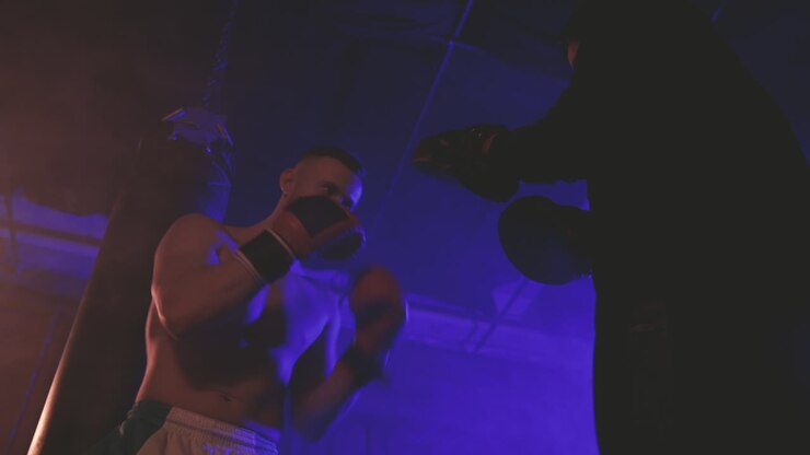 Pugile a torso nudo si riscalda colpendo i guanti da sparring 1