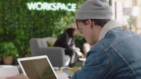 young student using laptop computer working on creative project browsing online research writing notes enjoying study in trendy office workspace