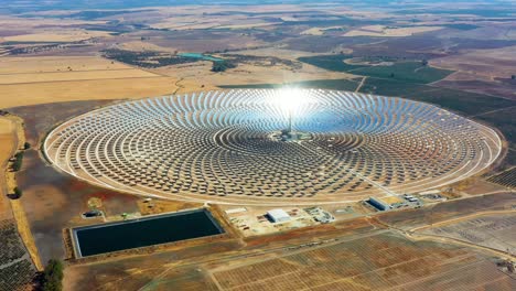 aerial view of a large circular power plant of solar panels in spain. there is the reflection of the sun in the the panels which produce renewable energy - environment concept