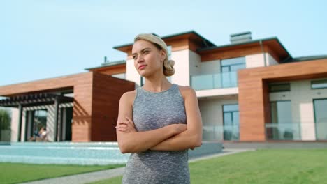 concentrated woman standing near luxury house. serious woman relaxing near villa