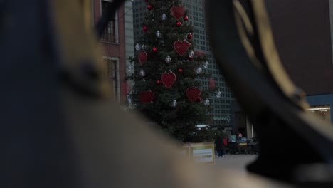 tilt-up revealing shot of decorative christmas tree outdoor adorned with hearts and baubles in amsterdam, netherlands