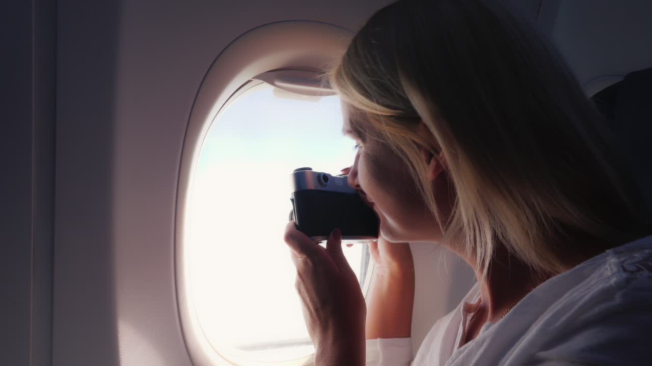 한 여성이 비행기 창에서 아름다운 풍경을 촬영합니다.